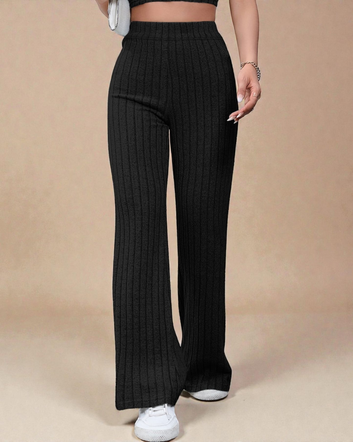 Person wearing black ribbed wide-leg pants on a beige background