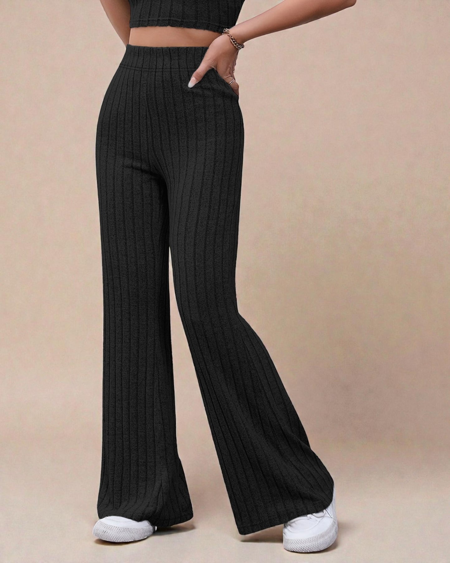 Person wearing black ribbed wide-leg pants on a beige background