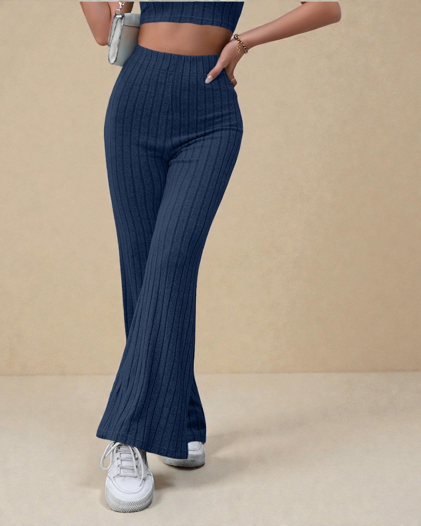 Navy ribbed pants worn by a person on a beige background