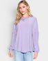 Woman wearing a light purple blouse and light blue jeans on a white background