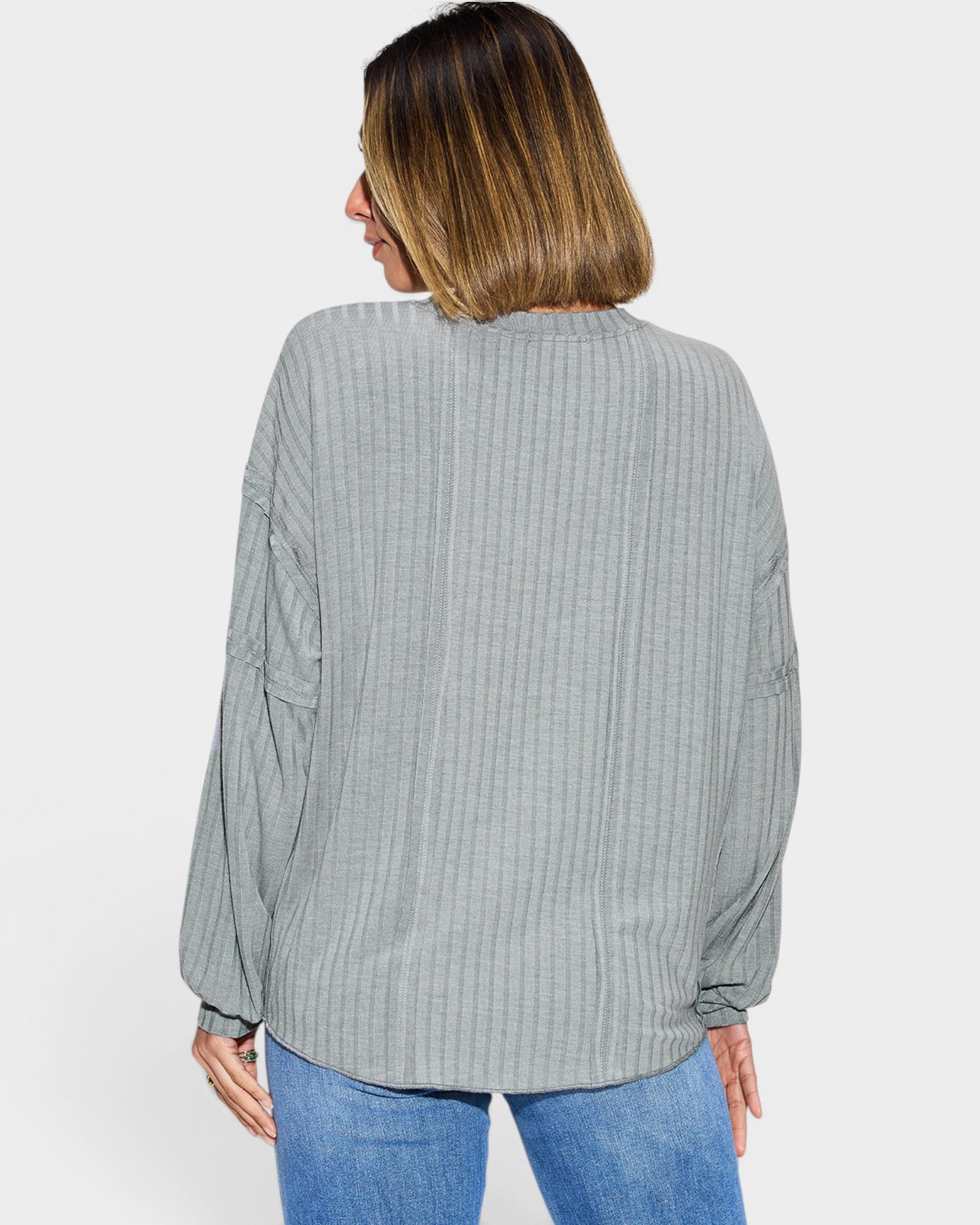 Woman wearing a light gray ribbed long-sleeve shirt on a white background