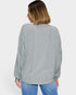 Woman wearing a light gray ribbed long-sleeve shirt on a white background