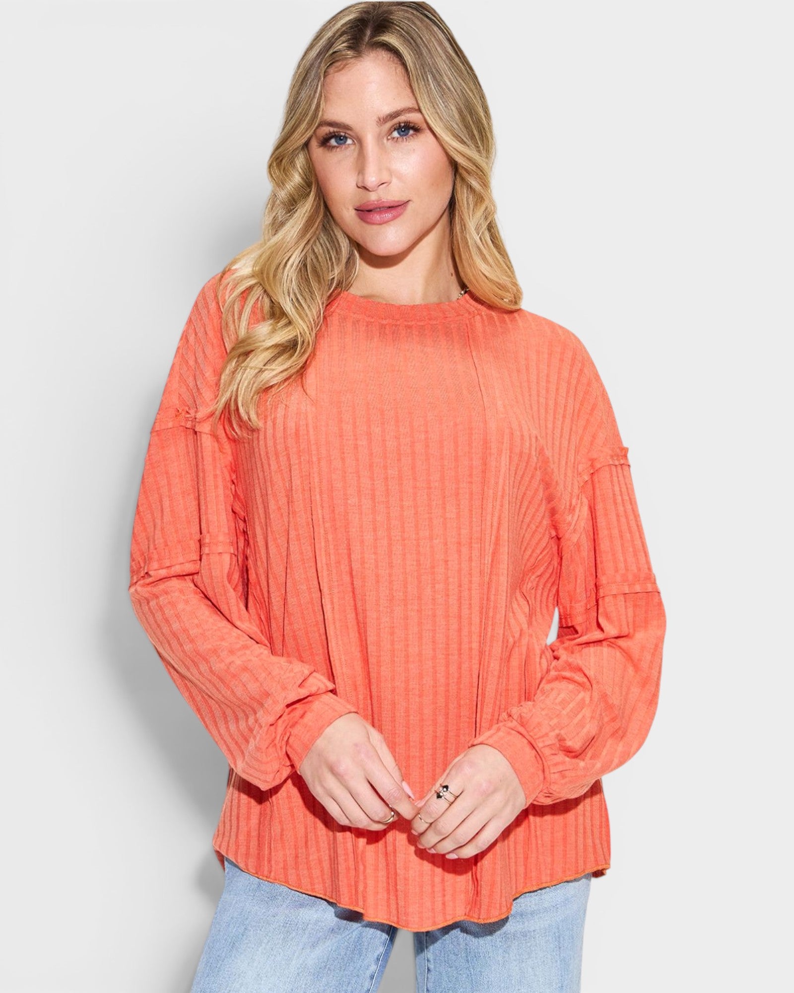 Woman wearing a coral ribbed sweater against a light background