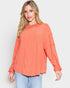 Woman wearing a coral ribbed sweater on a white background