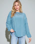 Woman wearing a light blue ribbed sweater and jeans against a plain background