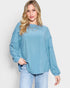 Woman wearing a light blue ribbed sweater and jeans on a white background