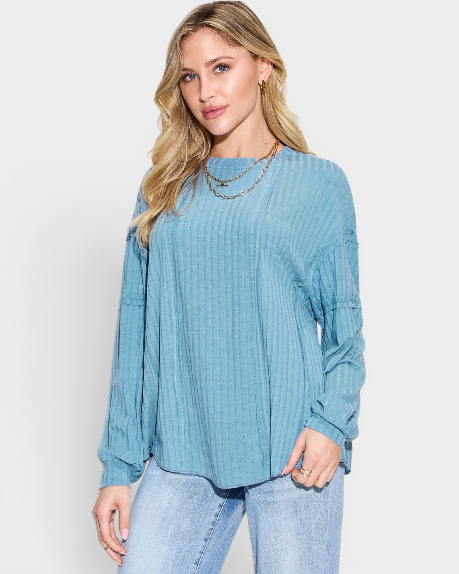 Woman wearing a blue ribbed long-sleeve top against a white background