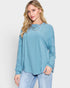 Woman wearing a blue ribbed long-sleeve top against a white background