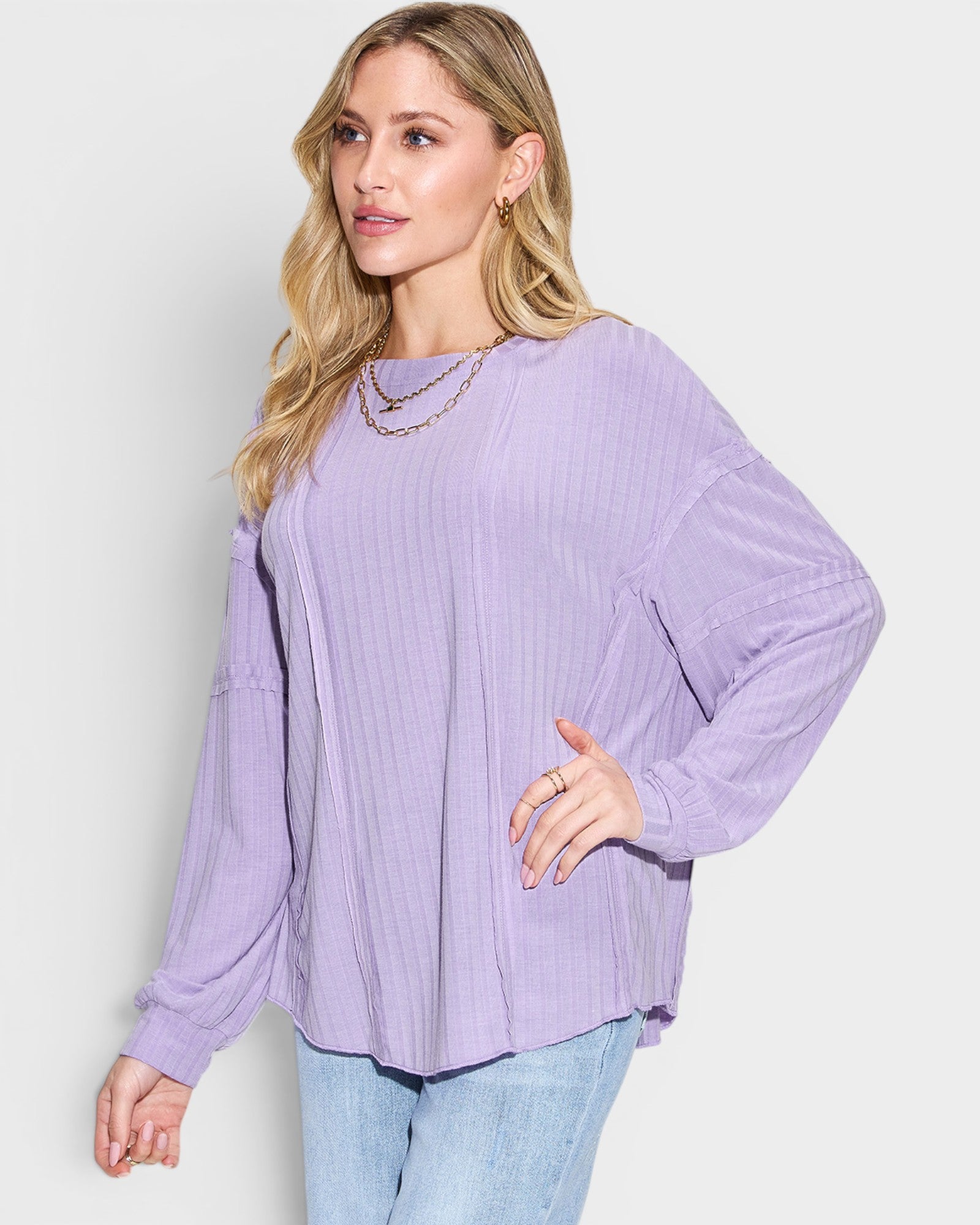 Woman wearing a purple ribbed sweater against a white background