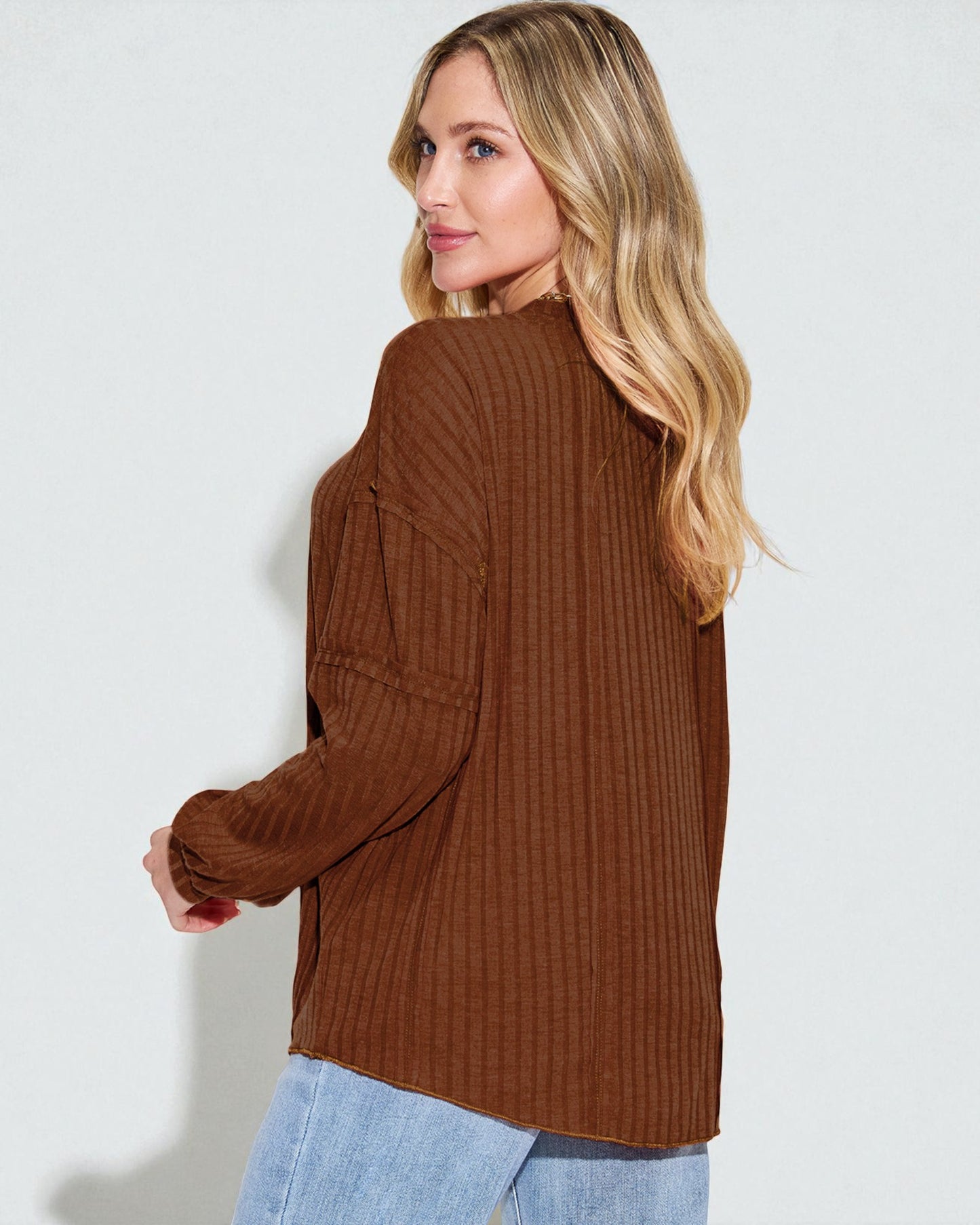Woman wearing a brown ribbed sweater against a white background
