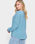 Woman wearing a light blue ribbed sweater against a white background
