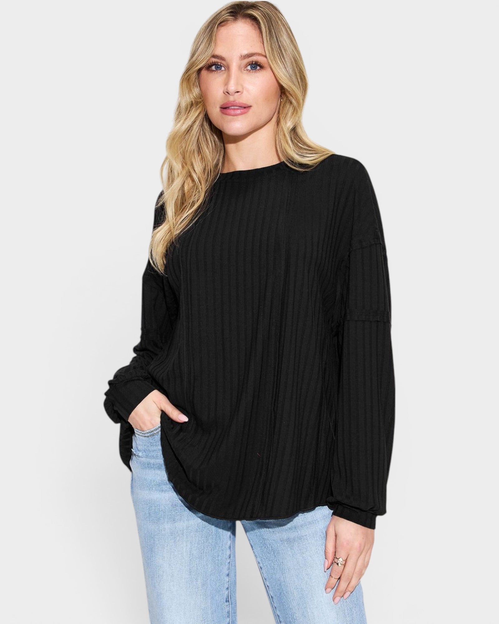 Woman wearing a black sweater and light blue jeans on a white background