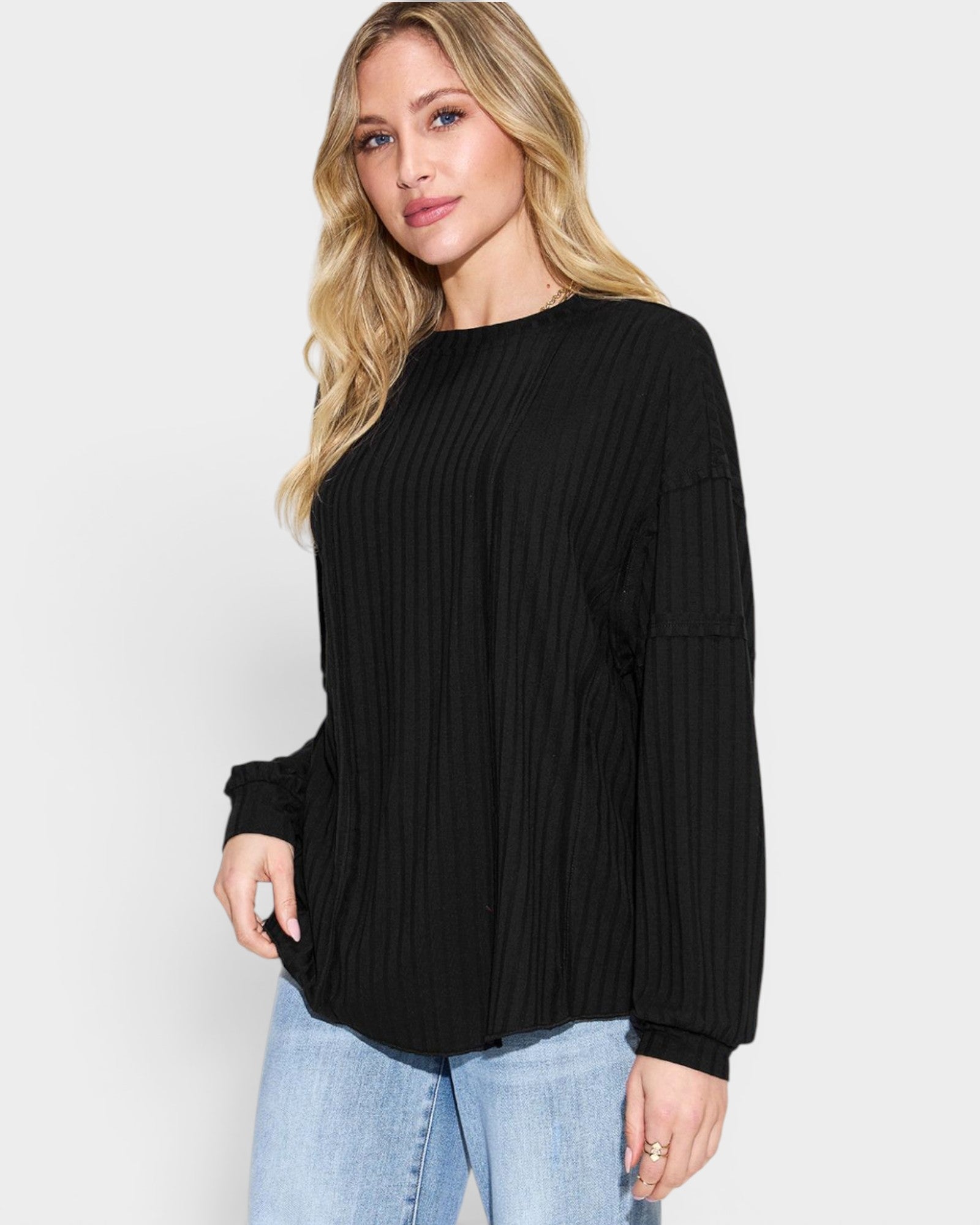 Woman wearing a black sweater and light blue jeans on a white background