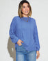 Woman wearing a blue ribbed sweater and jeans against a white background