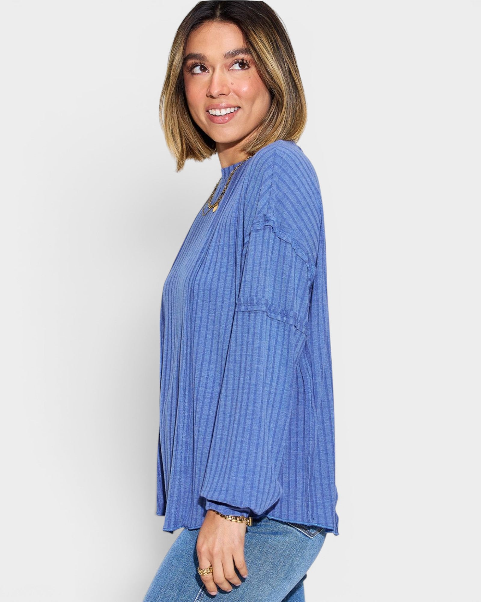 Woman wearing a blue ribbed sweater against a white background