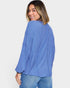 Woman wearing a blue ribbed sweater and jeans on a white background