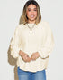 Woman wearing a light-colored blouse and blue jeans against a plain background