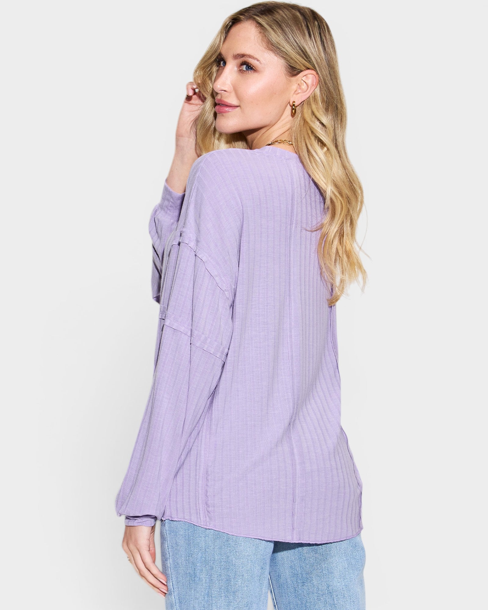Woman wearing a light purple ribbed sweater on a white background