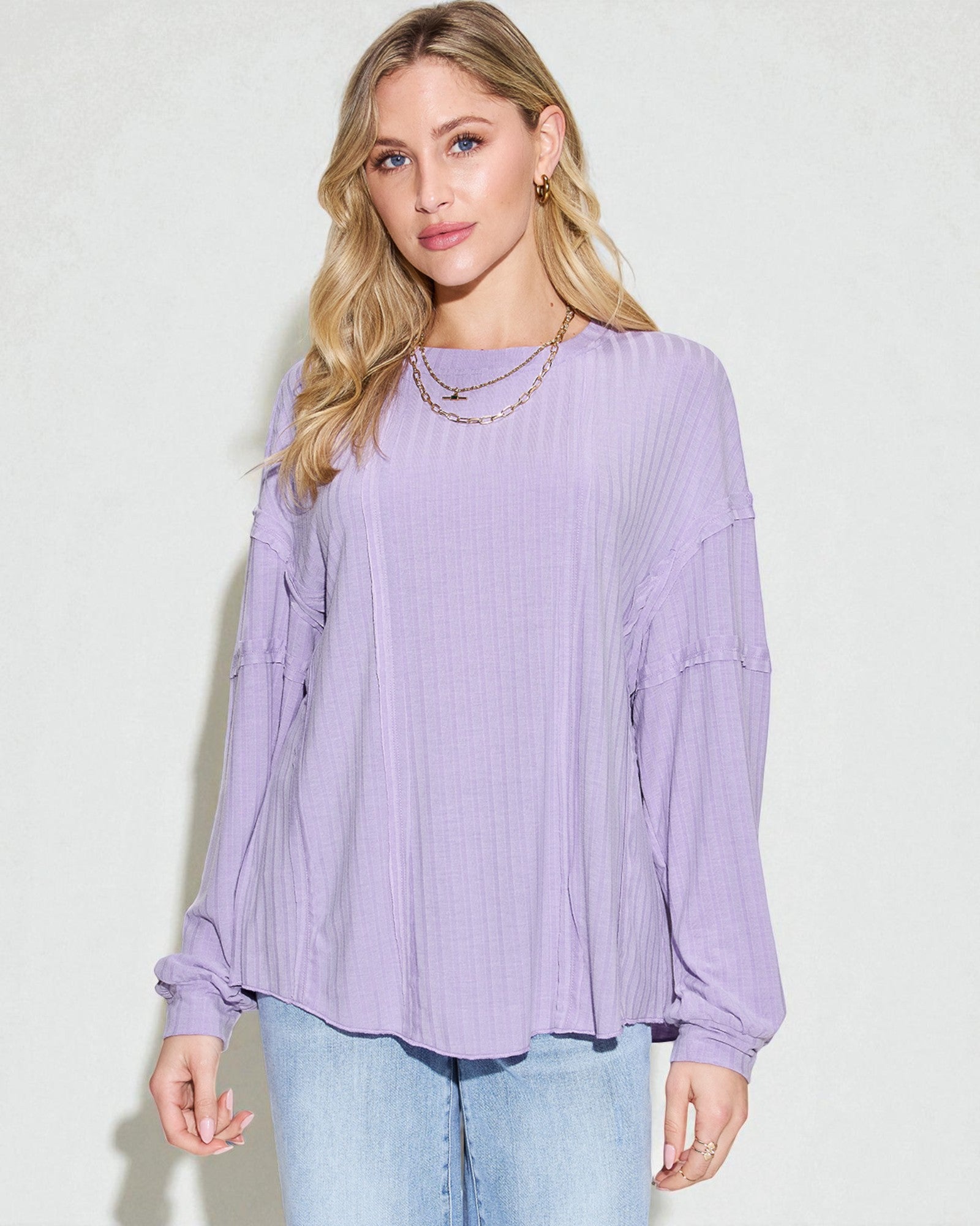 Woman wearing a light purple blouse and light blue jeans against a white background