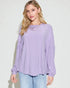 Woman wearing a light purple blouse and light blue jeans against a white background