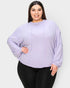Woman wearing a light purple ribbed sweater and black leggings on a white background