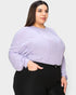 Woman wearing a light purple ribbed sweater and black pants on a white background