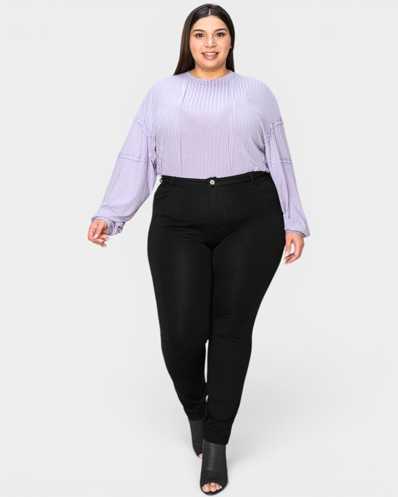 Woman wearing a light purple ribbed sweater and black pants on a white background