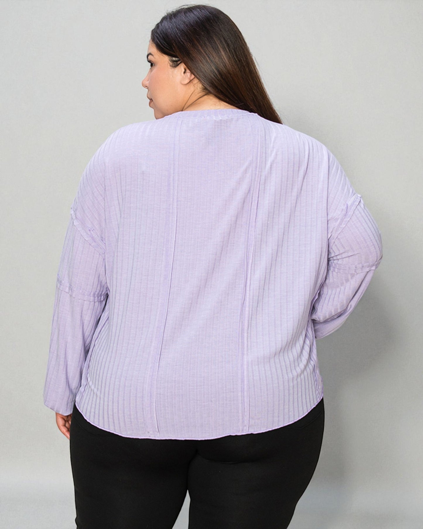 Person wearing a light purple ribbed sweater against a plain background