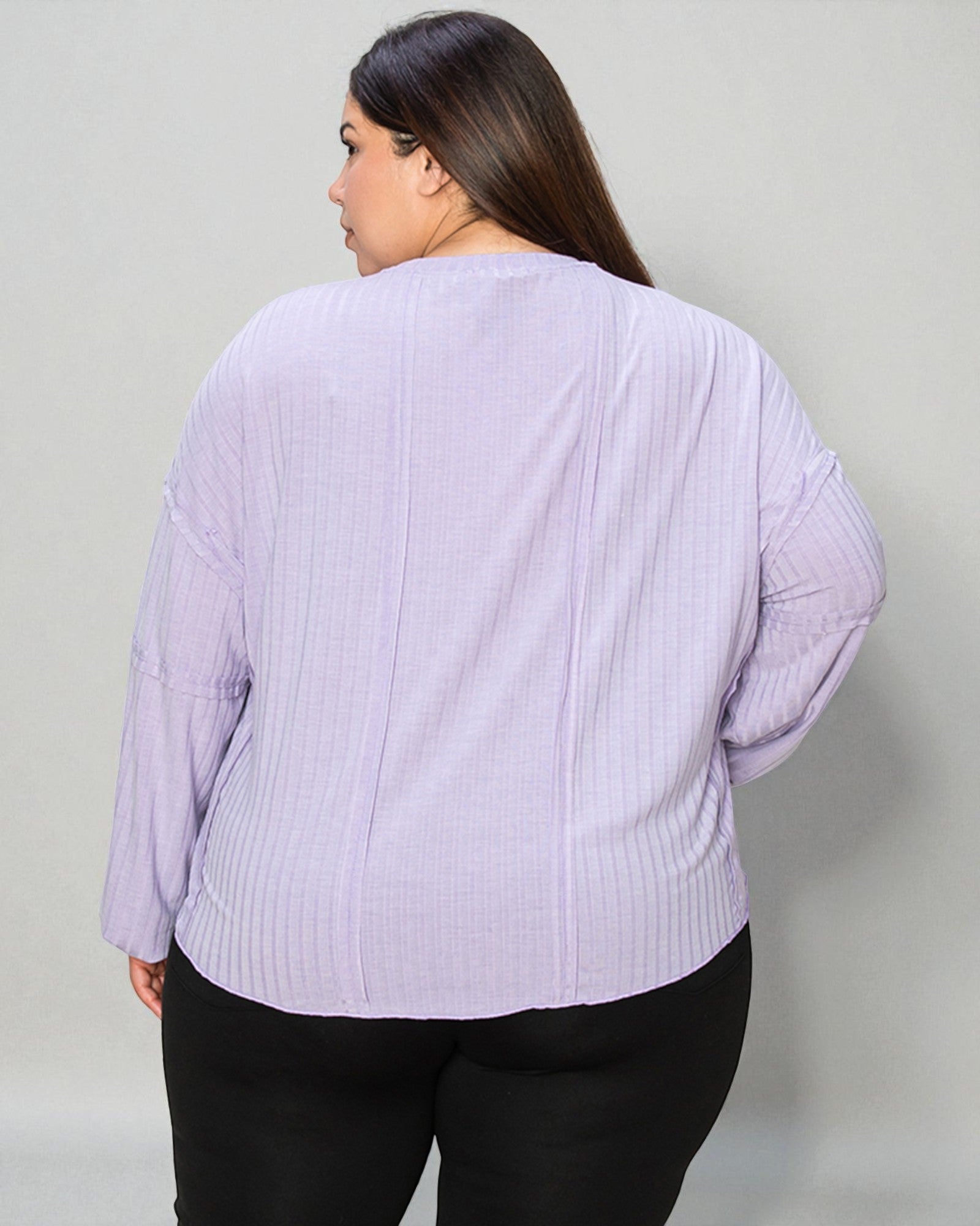 Person wearing a light purple ribbed sweater against a plain background