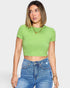 Woman wearing a green crop top and blue jeans against a white background