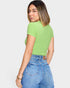 Woman wearing a green ribbed top and blue jeans on a white background