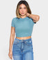 Woman wearing a blue ribbed crop top and jeans on a white background