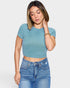 Woman wearing a blue ribbed crop top and jeans on a plain background