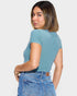Woman wearing a blue ribbed top and jeans on a plain background