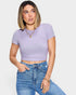 Woman wearing a purple ribbed crop top and blue jeans on a light gray background