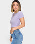 Woman wearing a purple ribbed crop top and blue jeans on a white background