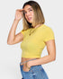 Woman wearing a yellow ribbed crop top and blue jeans on a white background