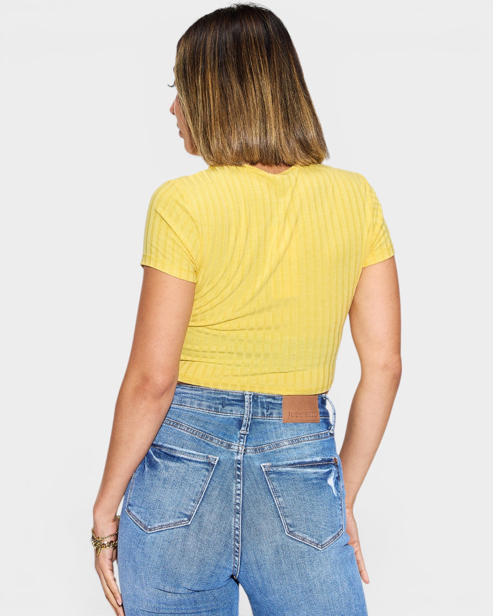 Person wearing a yellow top and blue jeans on a plain background