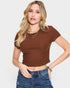 Woman wearing a brown ribbed top and blue jeans on a white background
