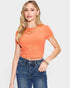 Woman wearing an orange ribbed top and blue jeans on a light gray background