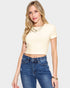 Woman wearing a yellow crop top and blue jeans against a white background