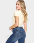 Woman wearing a yellow top and blue jeans on a plain background