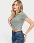 Woman wearing a green ribbed crop top and blue jeans on a white background