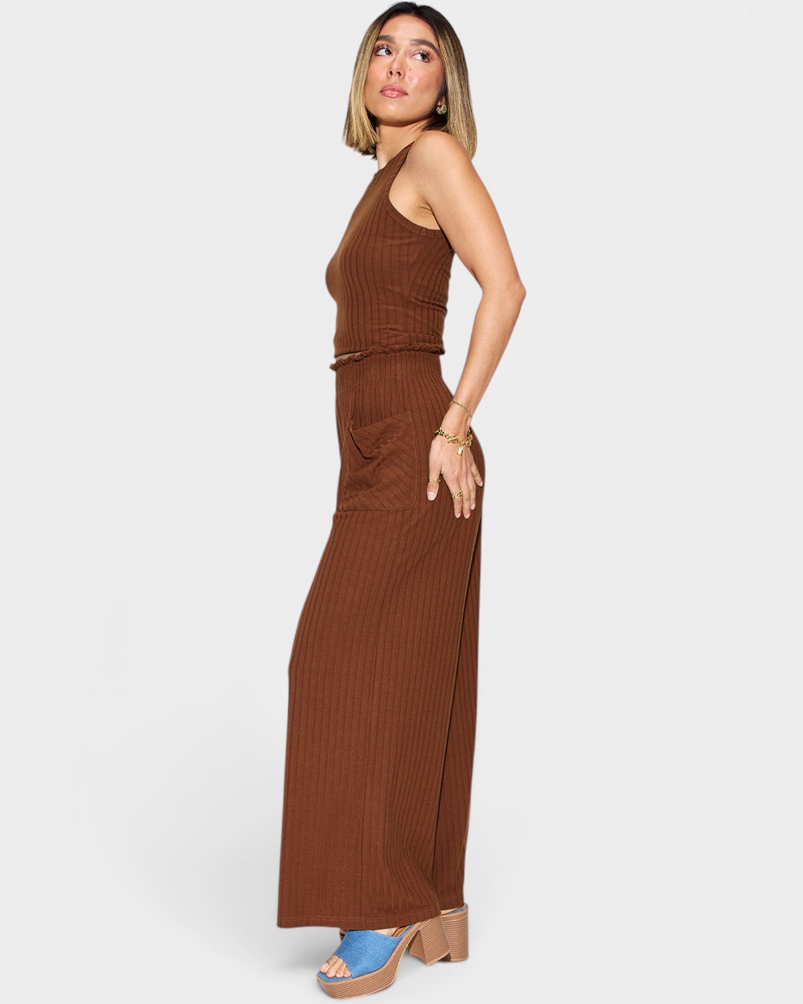 Woman wearing a brown ribbed dress on a white background