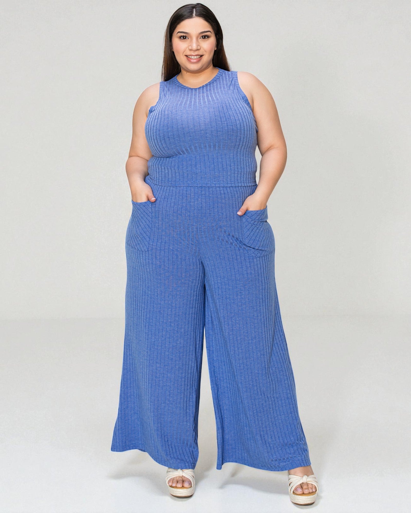 Woman wearing a blue ribbed jumpsuit on a white background