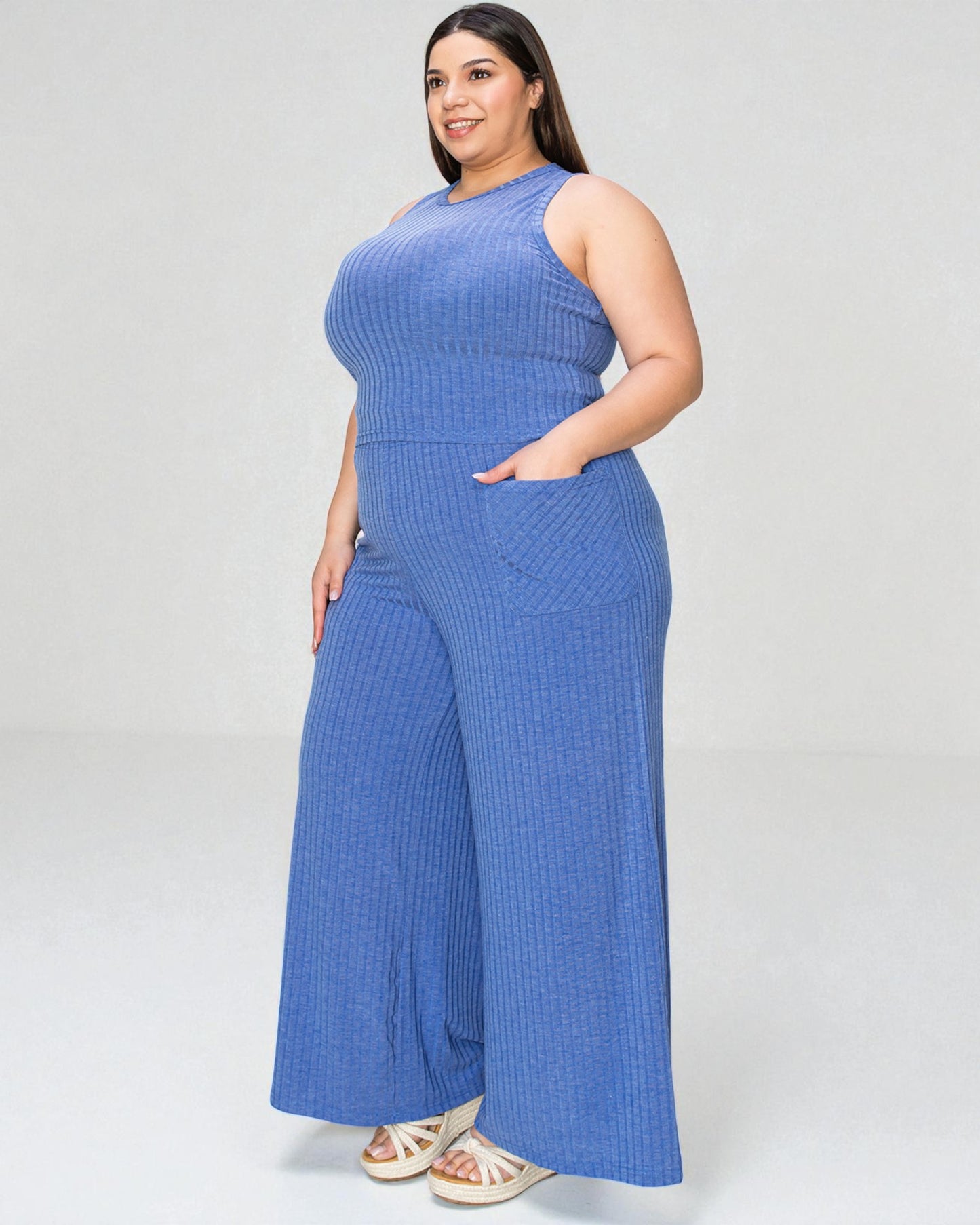 Woman wearing a blue ribbed jumpsuit on a white background