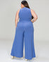 Woman wearing a blue ribbed jumpsuit on a plain background