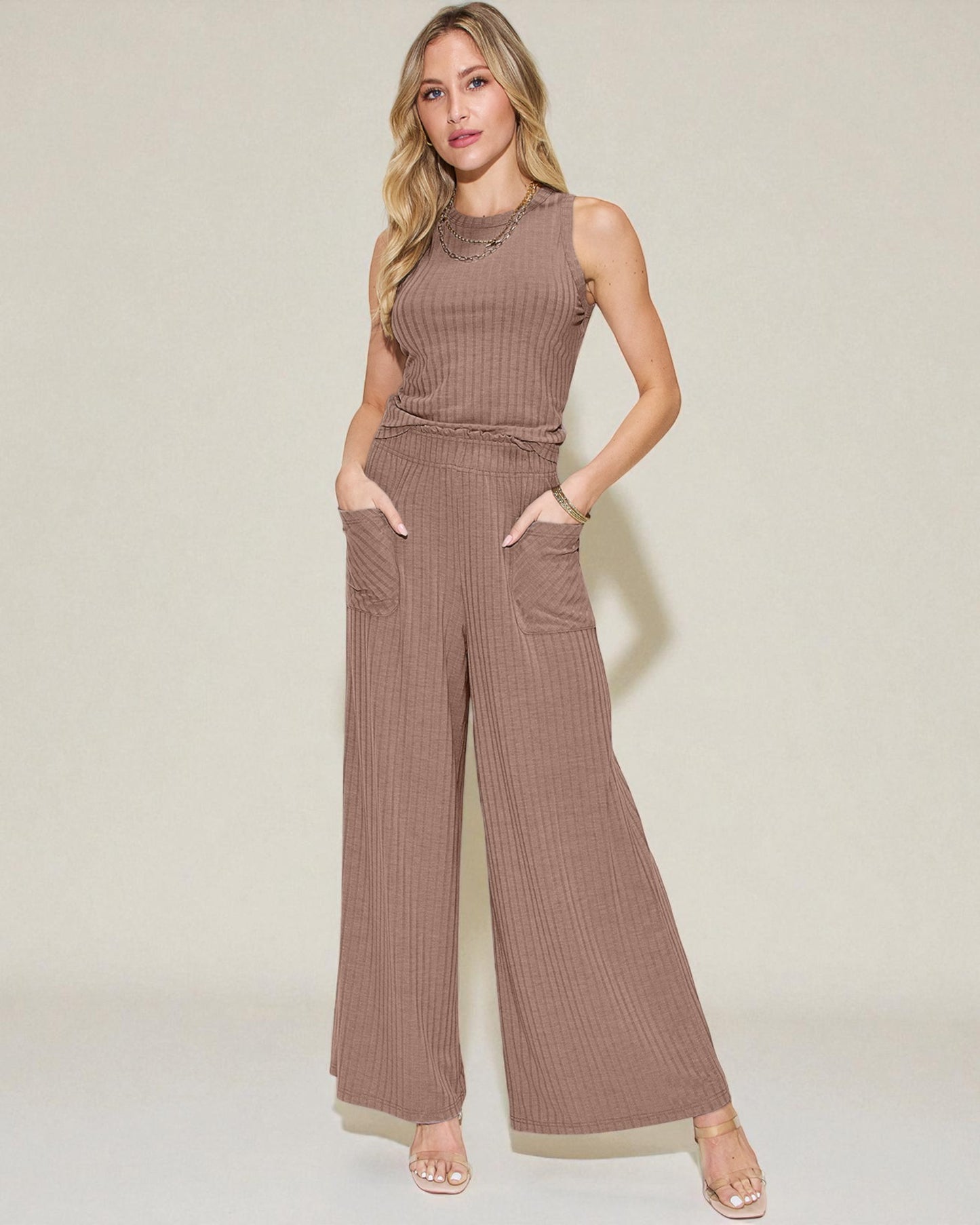 Woman wearing a brown ribbed jumpsuit on a beige background