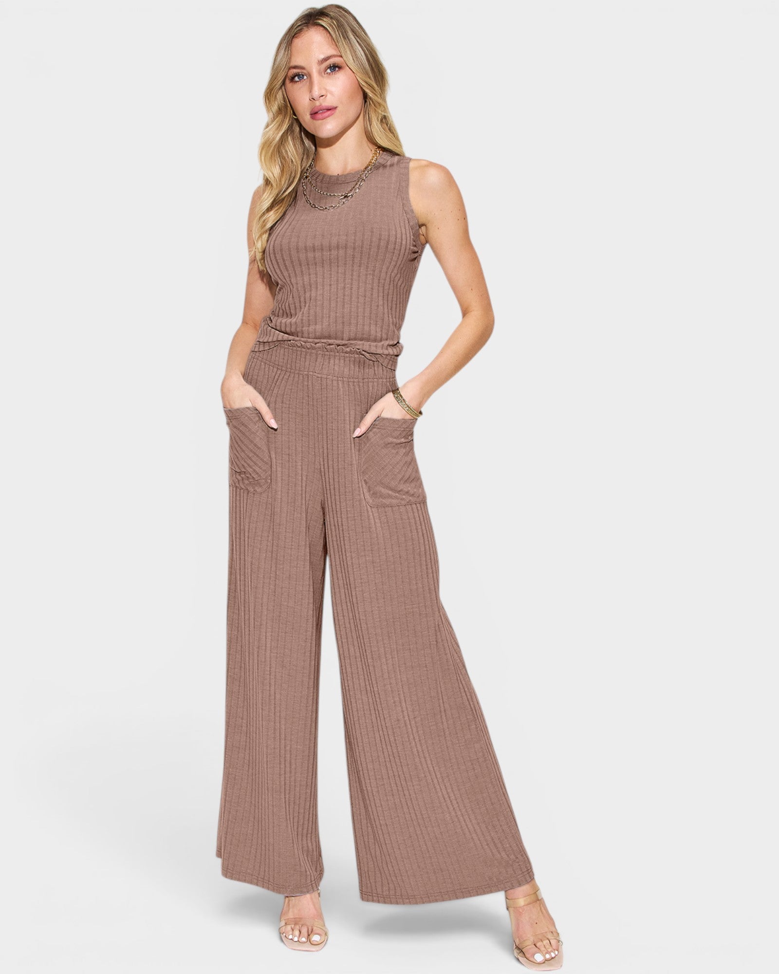 Woman wearing a brown ribbed jumpsuit on a light gray background