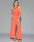 Woman wearing a coral jumpsuit on a gray background
